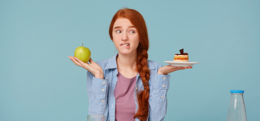 Garota jovem confusa entre dois alimentos.